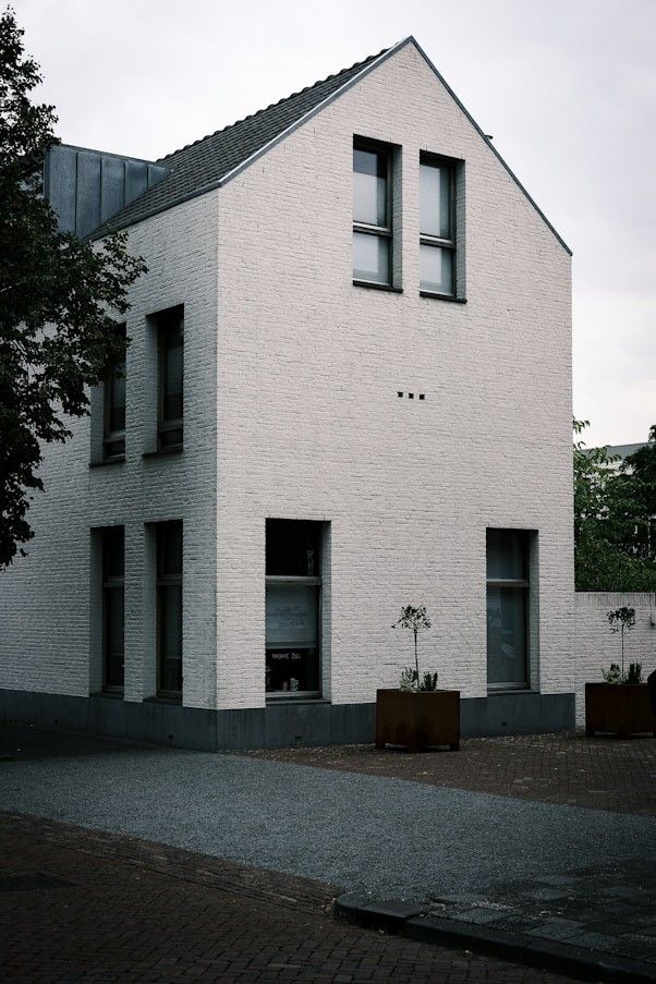 Three-storey whitewashed brick townhouse with deep-set windows and planters at the door