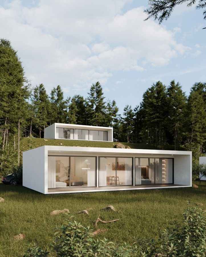 Long white villa with full-height glazing set into a forest clearing