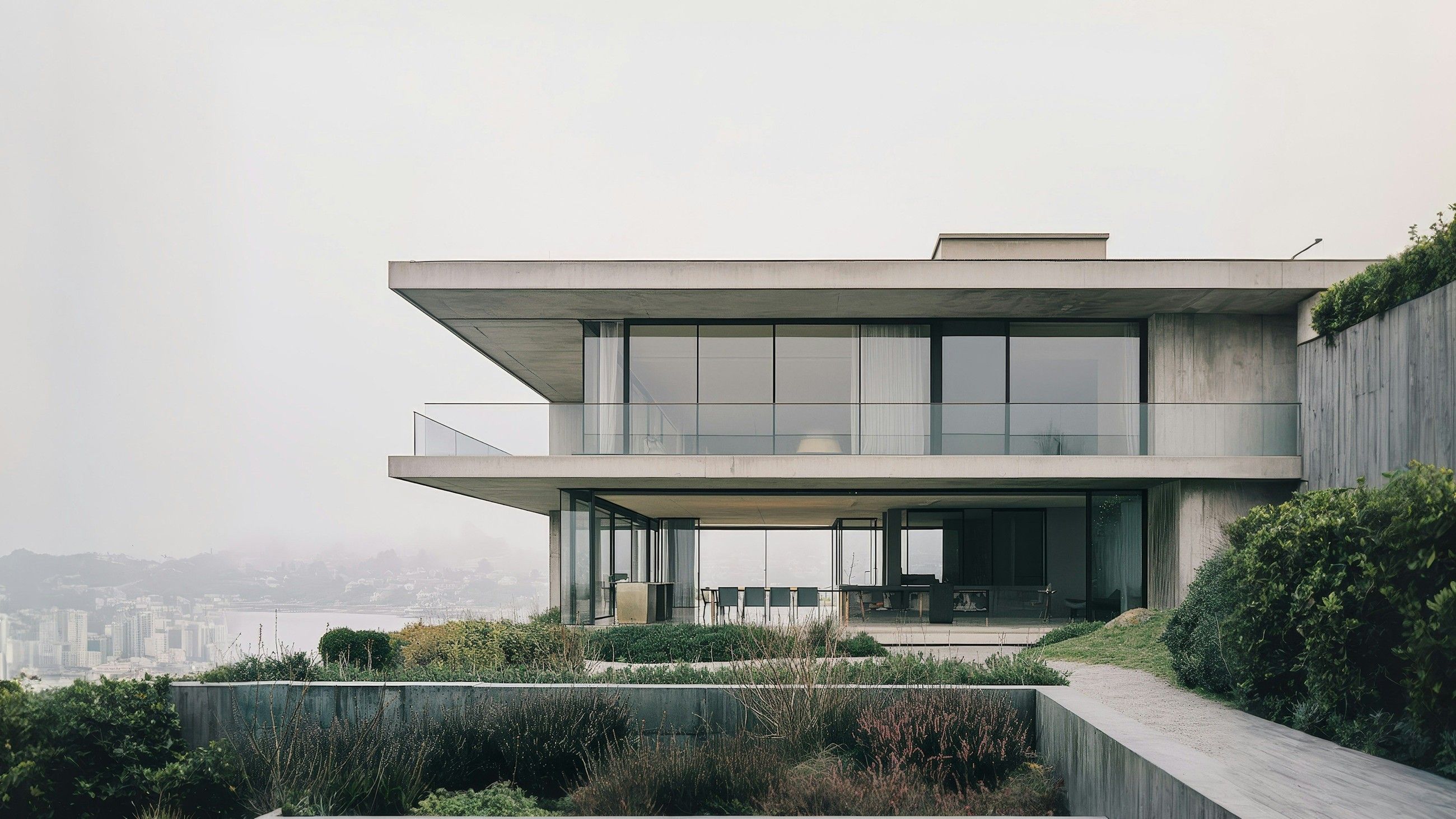 Concrete house with stacked glazed floors and terraces on a hillside above the water