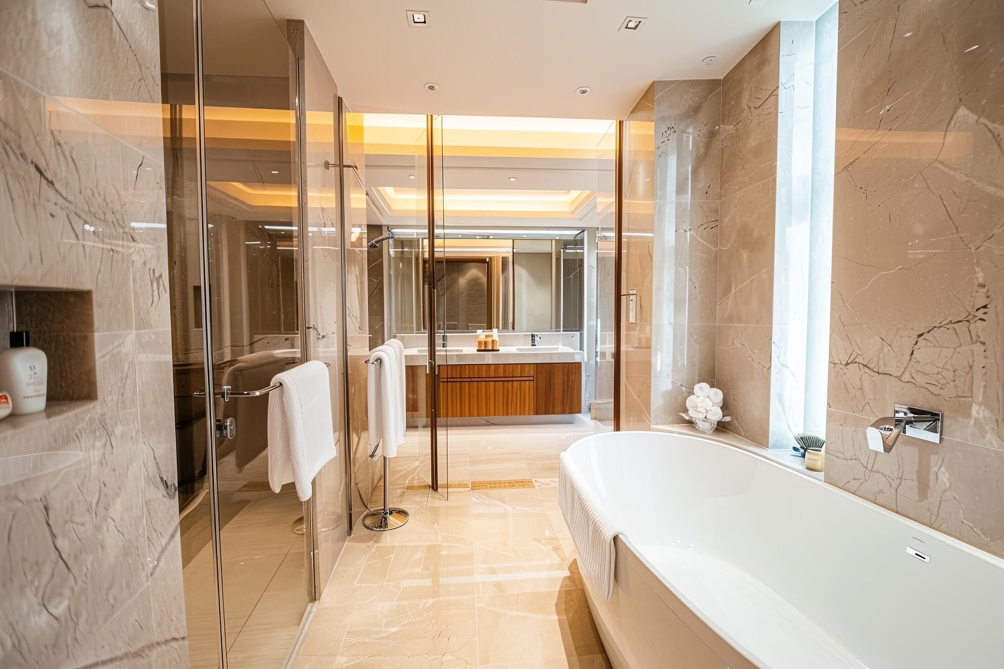Marble bathroom with a freestanding bath, glass shower and warm lighting